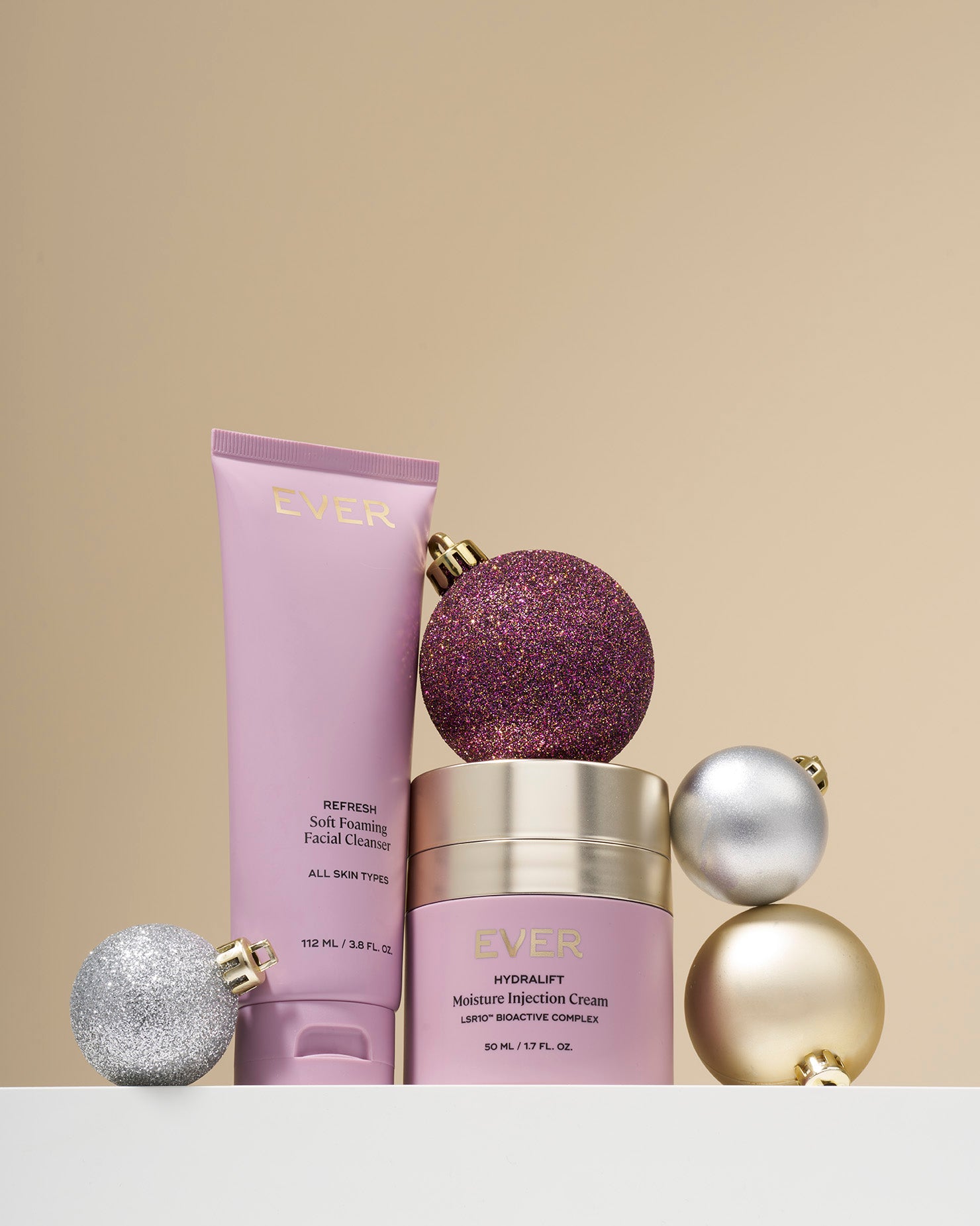 EYEN skin care products, Soft Foaming Cleanser and Hydralift Injection Cream with decorative baubles on a beige background